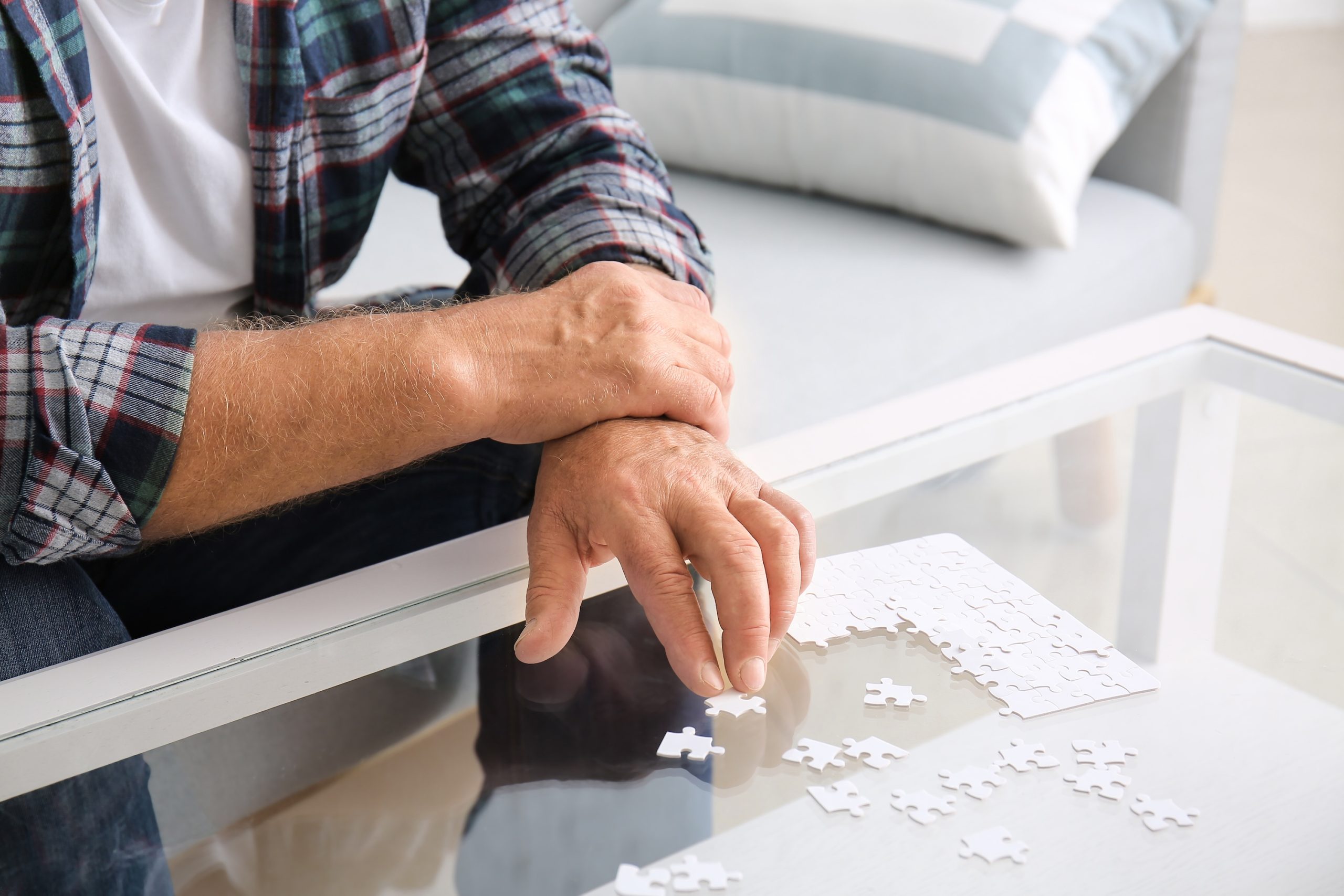 Älterer Mann beim Puzzeln am Couchtisch, er hält seine zitternde Hand fest, Beispielfoto für Zittern / Tremor, Neurologische Praxis Dr. Hartmut Bauer, Euskirchen Älterer Mann beim Puzzeln am Couchtisch, er hält seine zitternde Hand fest, Beispielfoto für Zittern / Tremor, Neurologische Praxis Dr. Hartmut Bauer, Euskirchen