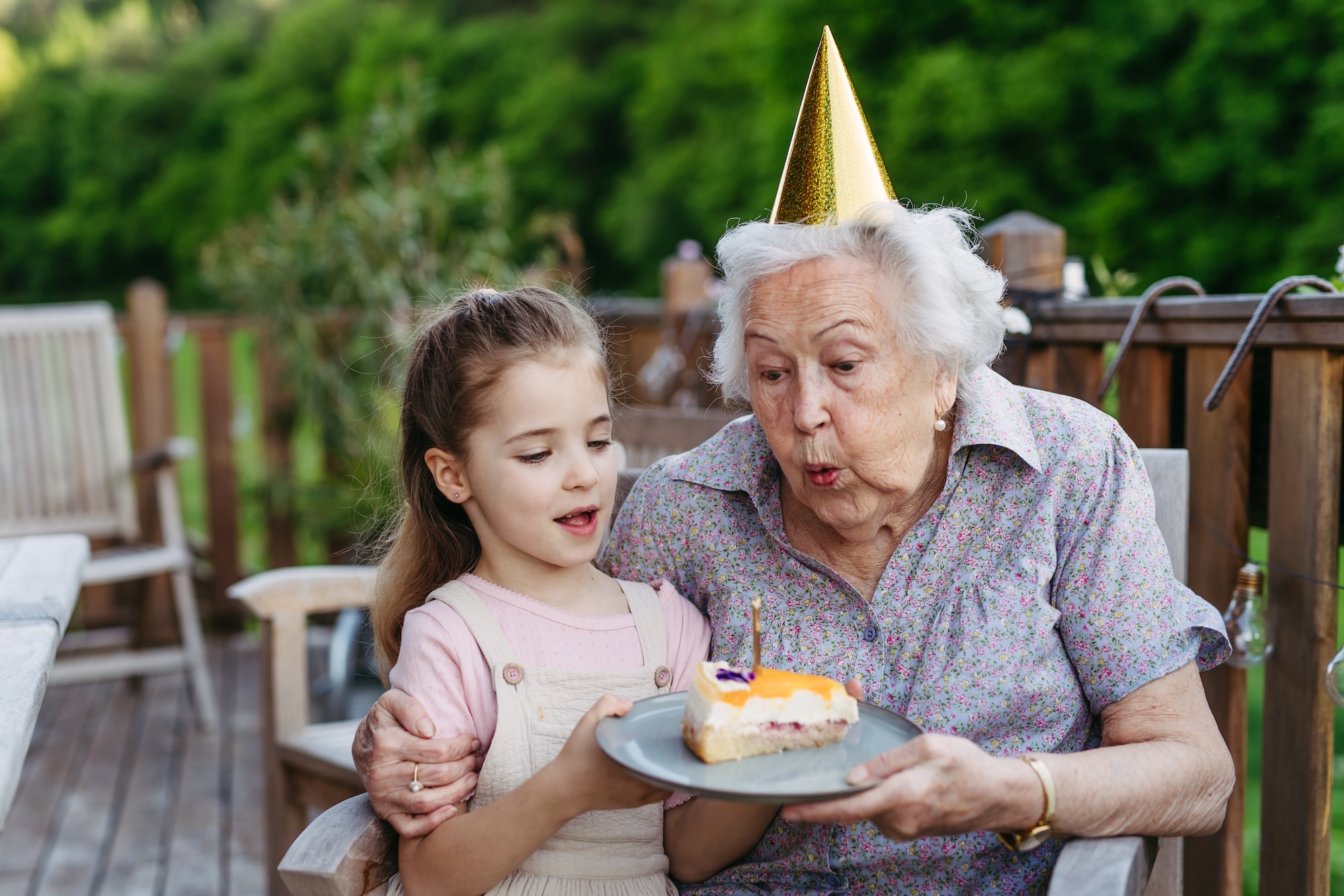 Großmutter feiert Geburtstag mit der Enkeltochter, sie haben Kuchen und Oma pustet eine Kerze aus, Beispielfoto für Alzheimer / Demenz, Neurologische Praxis Dr. Hartmut Bauer, Euskirchen