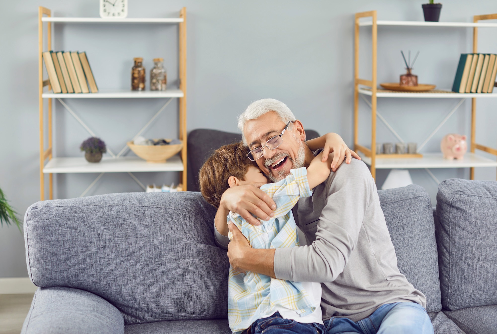 Großvater freut sich und umarmt seinen Enkel, beide sitzen auf der Couch, Beispielfoto für Alzheimer / Demenz, Neurologische Praxis Dr. Hartmut Bauer, Euskirchen