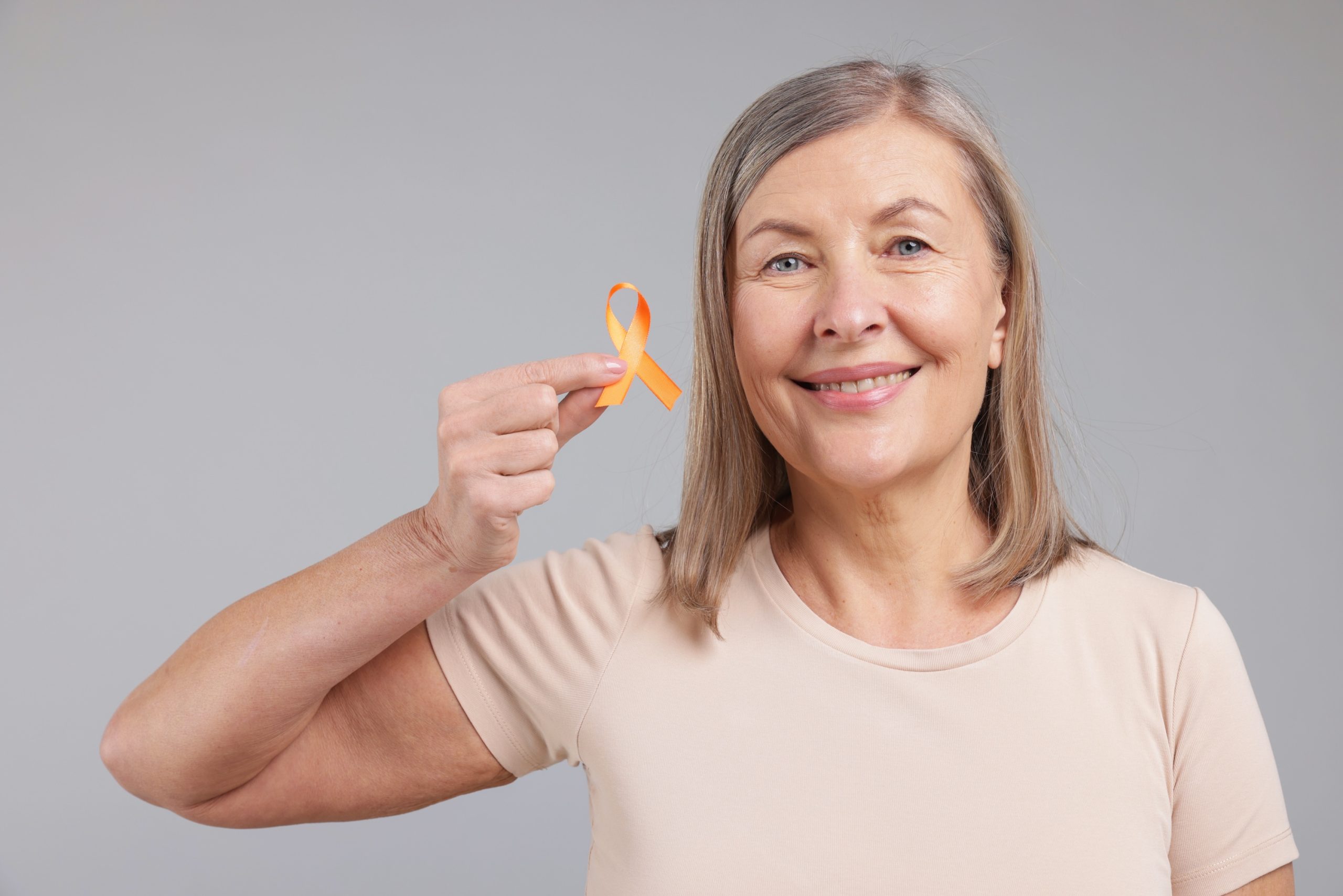 Frau mit orangefarbener kleiner Schleife in der Hand, Beispielfoto für Multiple Sklerose, Neurologische Praxis Dr. Hartmut Bauer, Euskirchen Frau mit orangefarbener kleiner Schleife in der Hand, Beispielfoto für Multiple Sklerose, Neurologische Praxis Dr. Hartmut Bauer, Euskirchen