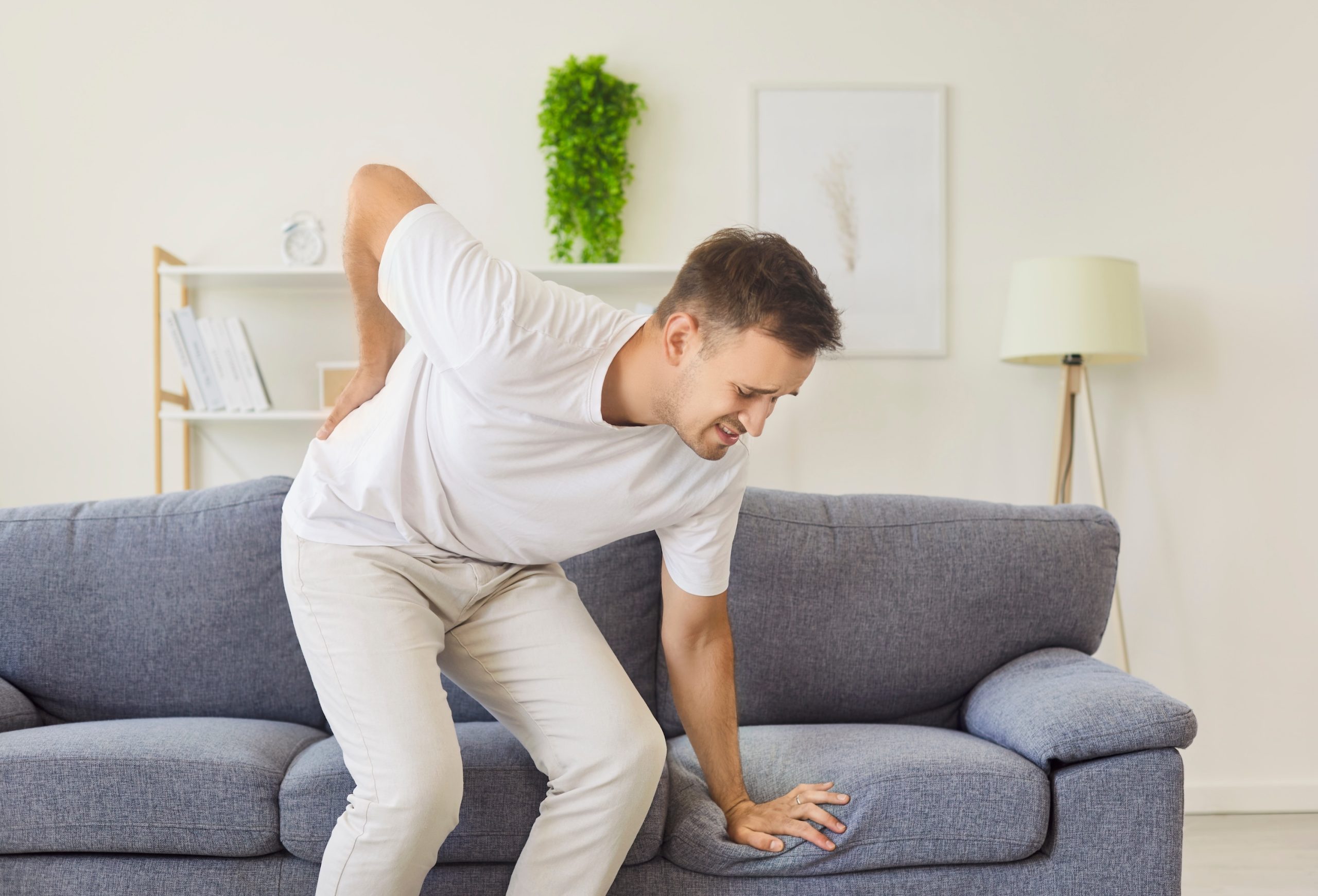 Junger Mann hat Schmerzen im Bereich der Bandscheiben und kann fast nicht von der Couch aufstehen, Beispielfoto für verschiedene Arten von Rückenschmerzen, Neurologische Praxis Dr. Hartmut Bauer, Euskirchen Junger Mann hat Schmerzen im Bereich der Bandscheiben und kann fast nicht von der Couch aufstehen, Beispielfoto für verschiedene Arten von Rückenschmerzen, Neurologische Praxis Dr. Hartmut Bauer, Euskirchen